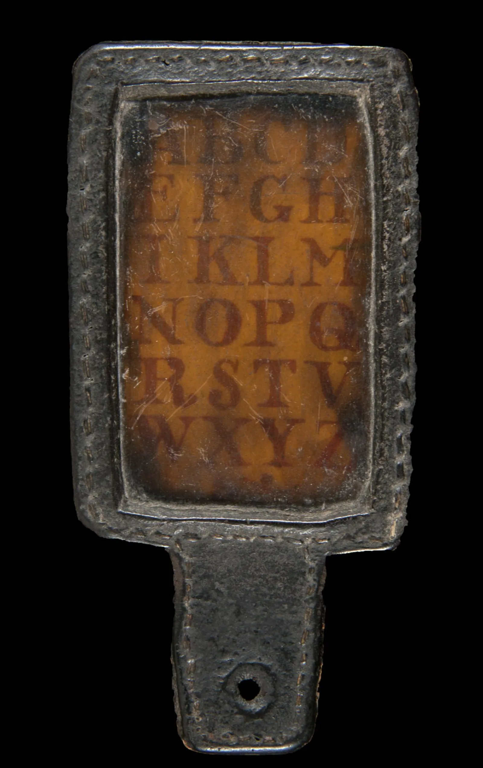 A small wooden paddle has a transparent screen running vertically. Under the screen is the alphabet. At the base of the paddle is a small hole.