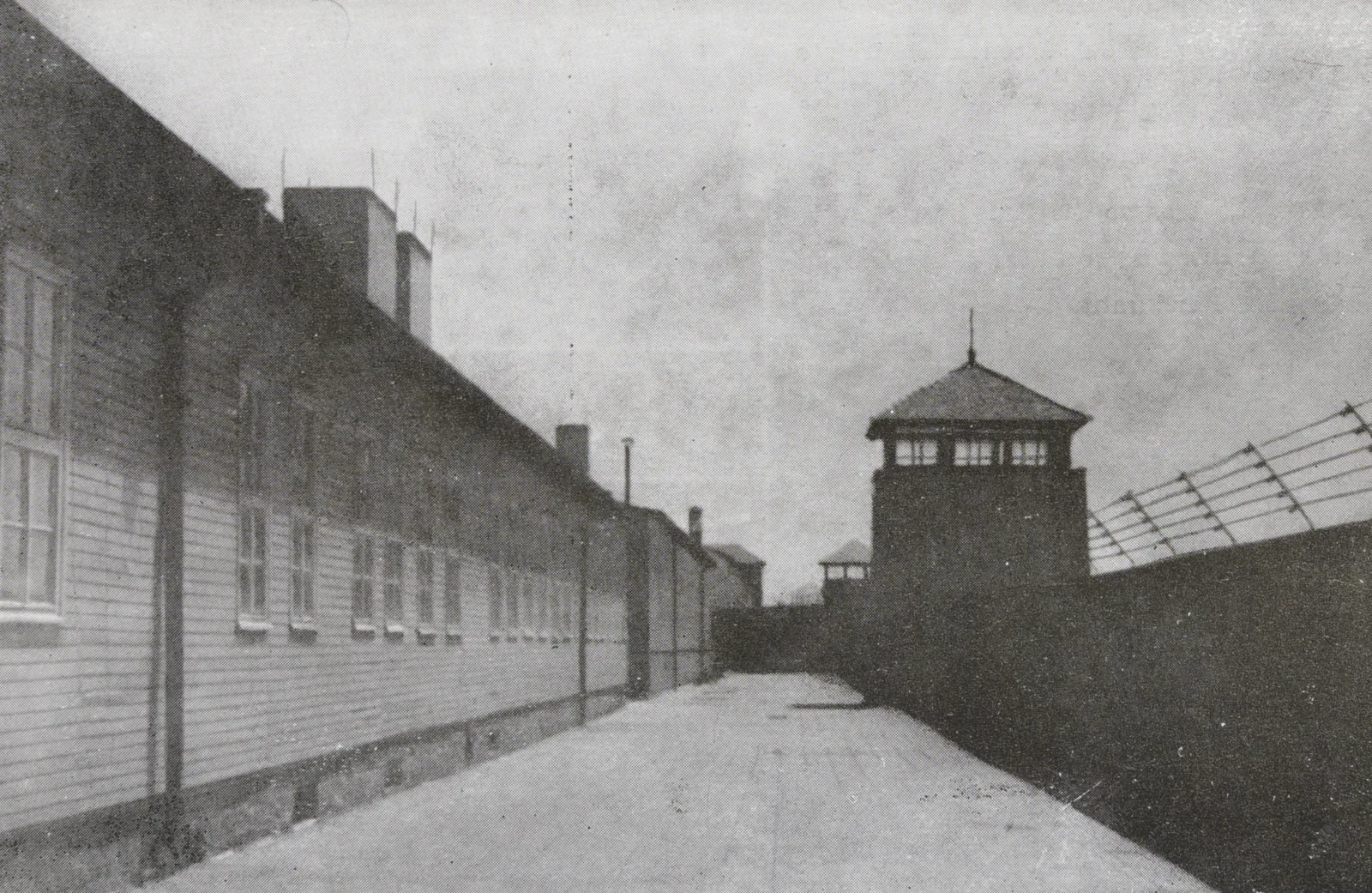 View of the concentration camp: a wall with barbed wire and a watchtower.